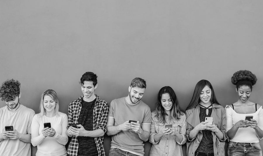 Young multiracial group of friends using mobile smartphone outdoor - Youth people and technology addiction concept - Black and white editing